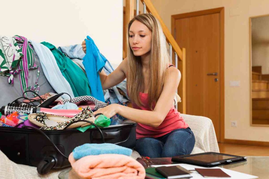 Woman in red shirt packing a suitcase for a girlfriend getaway.